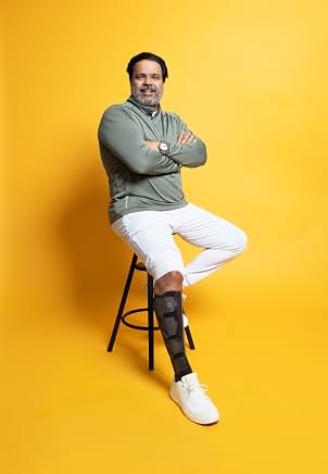 Sunil seated in a studio portrait against yellow