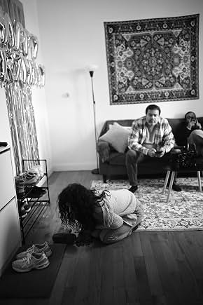 Black-and-white behind-the-scenes photo of Sunil seated on a living-room set
