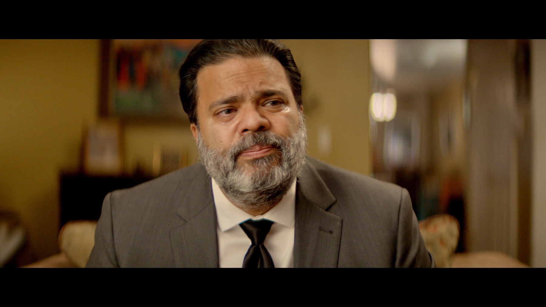 Sunil Saxena in a dramatic film scene, wearing a suit and tie